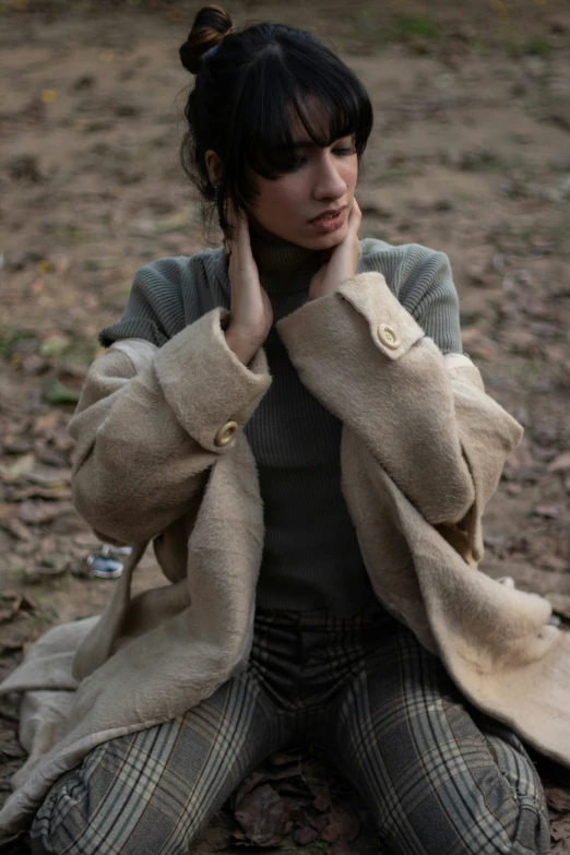 a woman sitting in the middle of the ground with her hands under her face