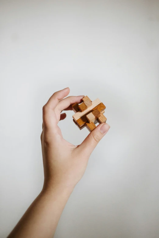 a woman's hand holding a toy cube of wood