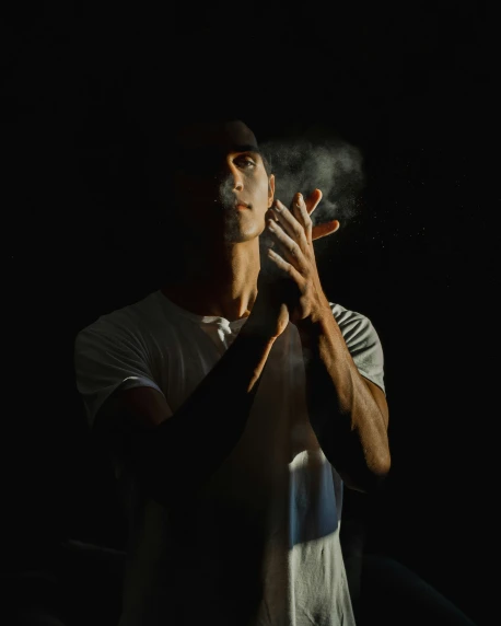 a man standing in the dark holding a cigarette