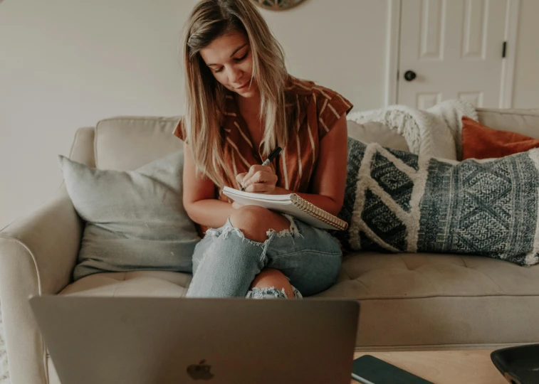 a woman sitting on the couch looking at her laptop