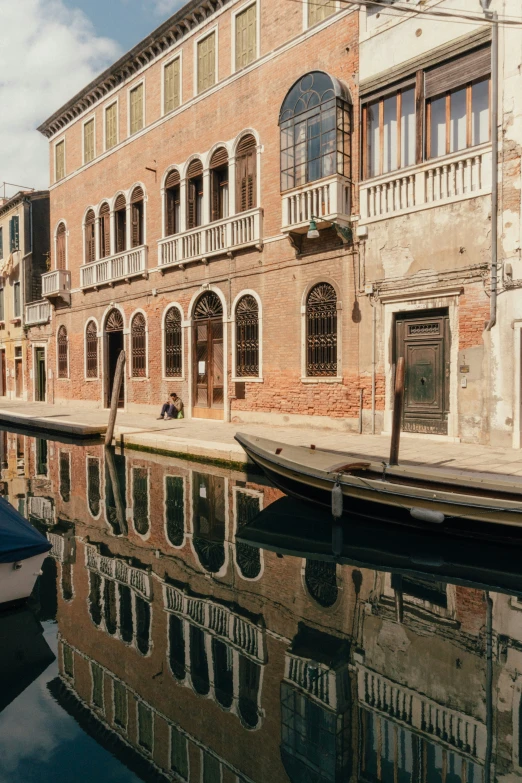 an old building reflecting in water next to boats