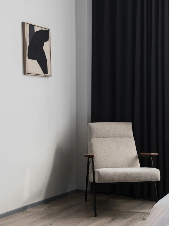 a modern chair and a small bed with black curtains