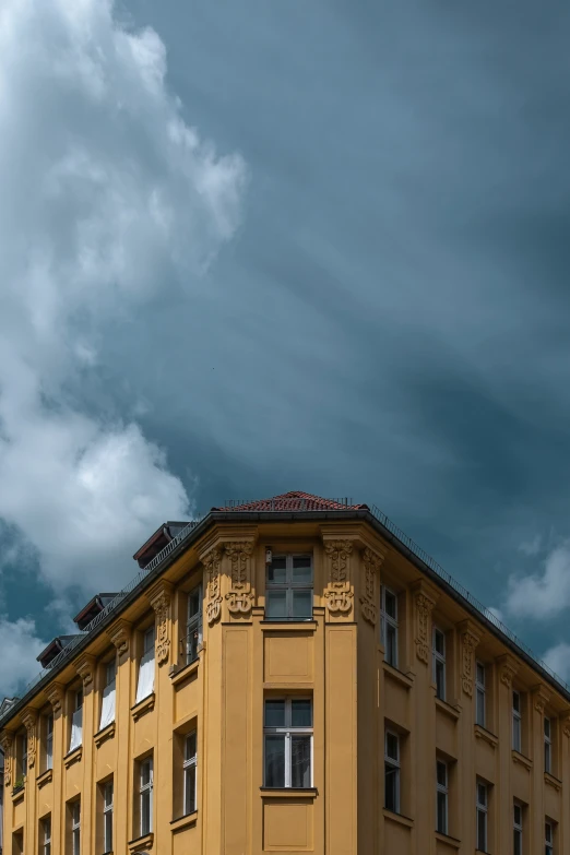 a tall yellow building sitting below a cloudy sky