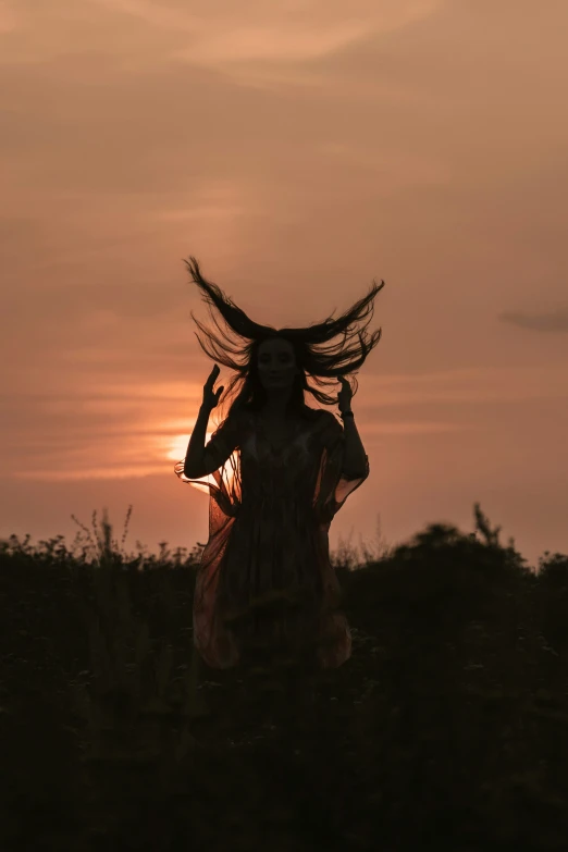 the back side of a womans head with the wind spinning and her hair up in a long dress