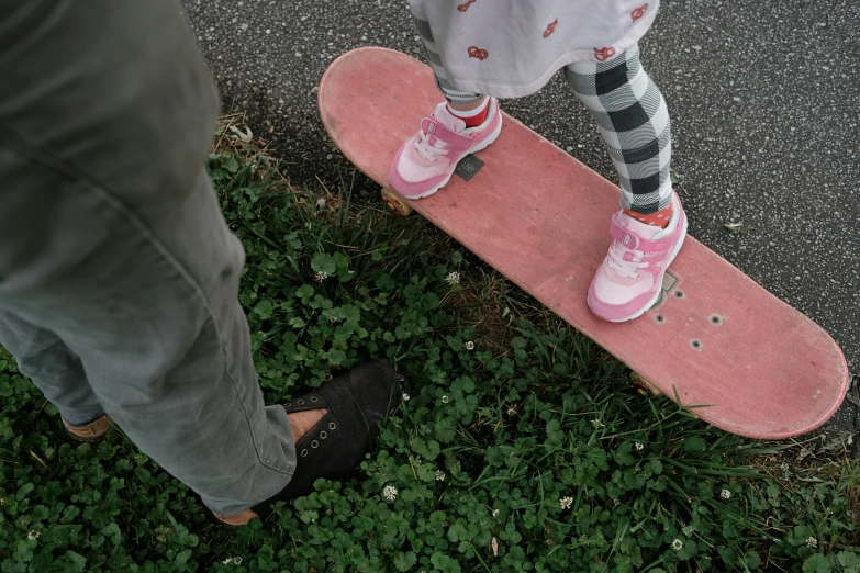 legs on skateboard next to feet wearing sneakers