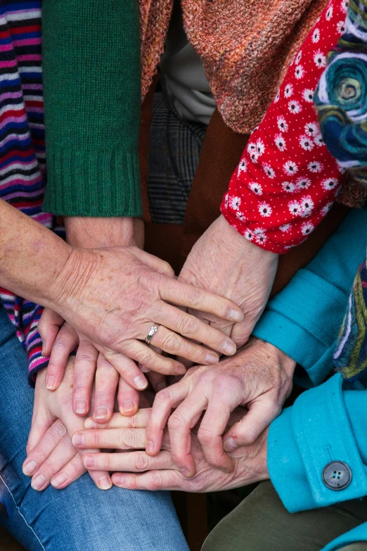 four hands holding each other with their fingers on their fingertips