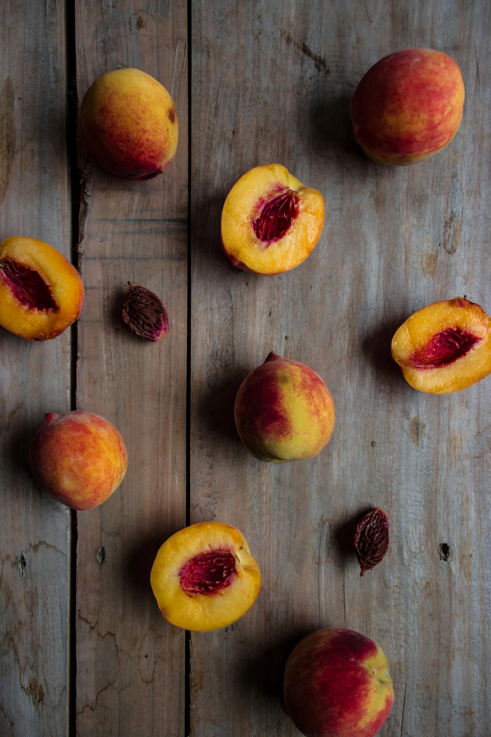 five peaches sitting on a table with a few sliced ones