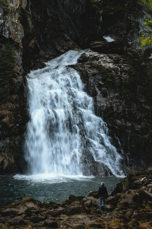 a man is standing in front of a waterfall