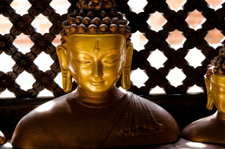 a bronze buddha statue sitting in front of a window