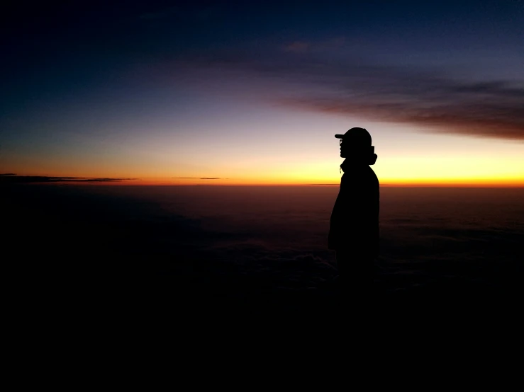 a man standing on top of a mountain watching the sun set