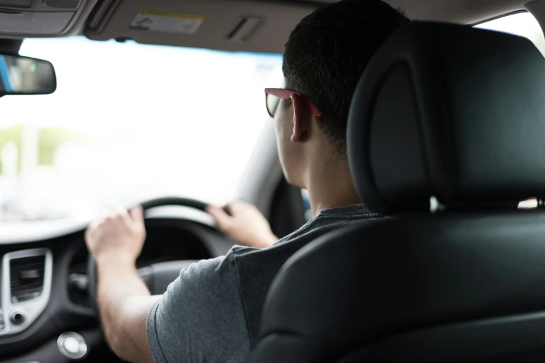 a man driving a car wearing black and glasses