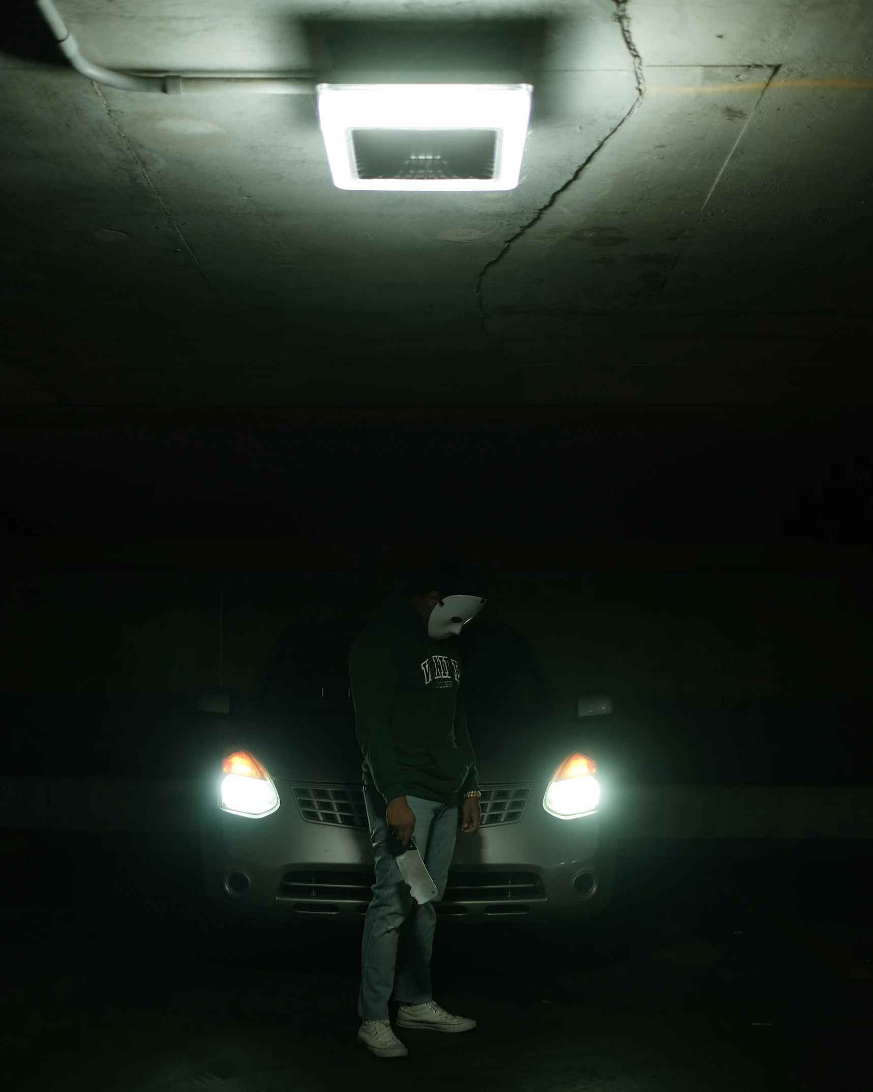 a man standing in front of a black car under a garage