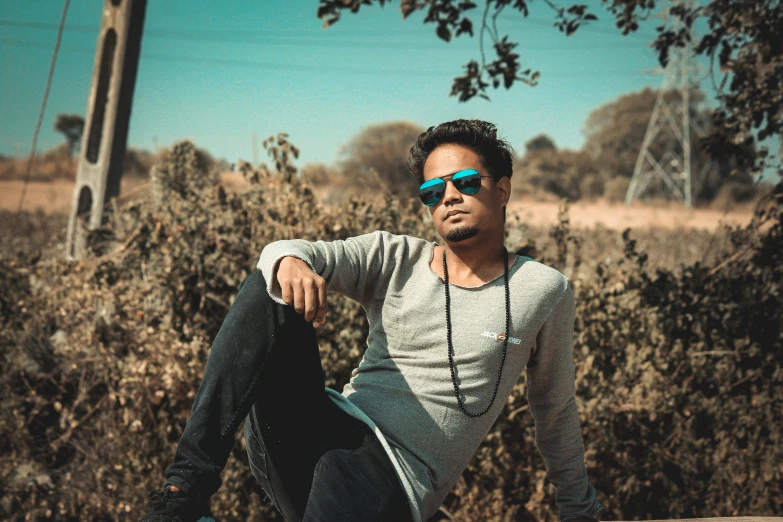 a man sits down wearing sunglasses and posing for the camera