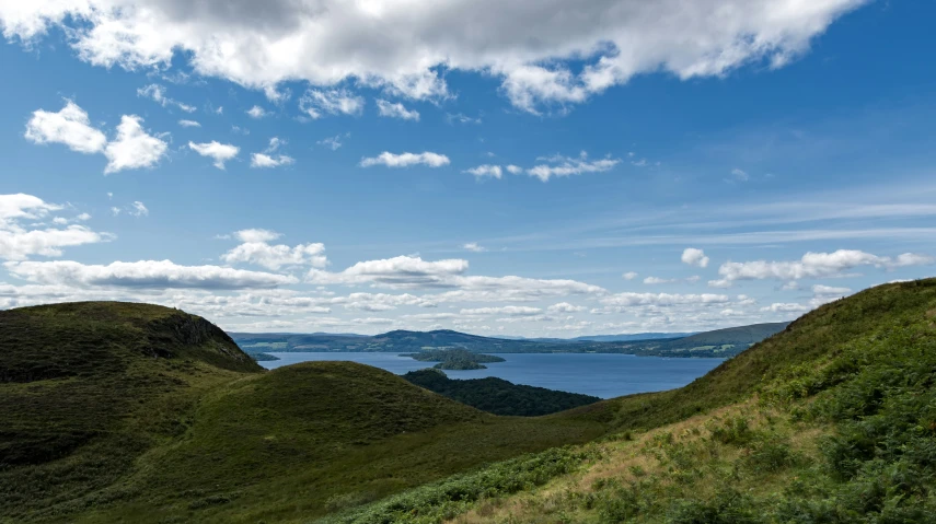 a blue sky with clouds over some hills