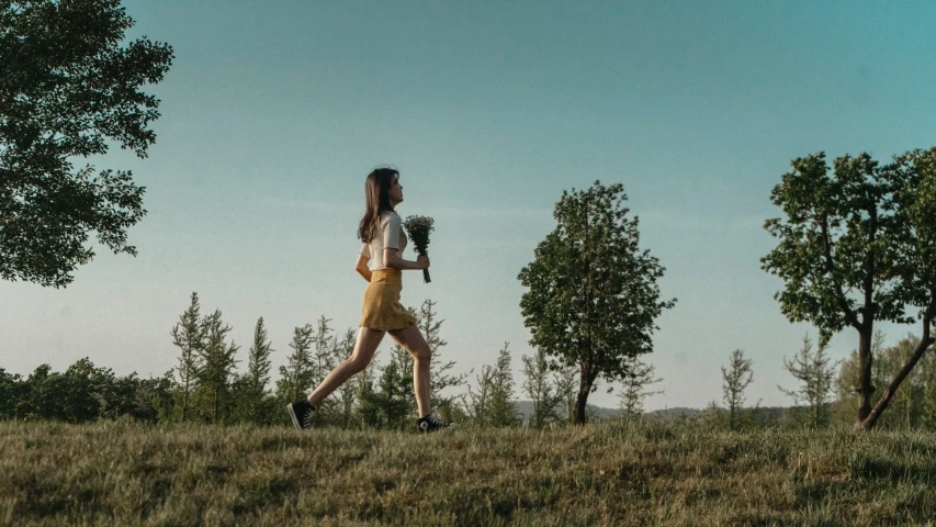 a woman is running in a grassy area with trees and other vegetation