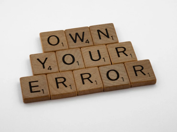 a close up of an spelled out scrabble with the word own your error