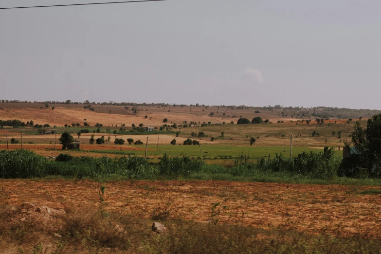 a grassy field with a road and buildings in the background