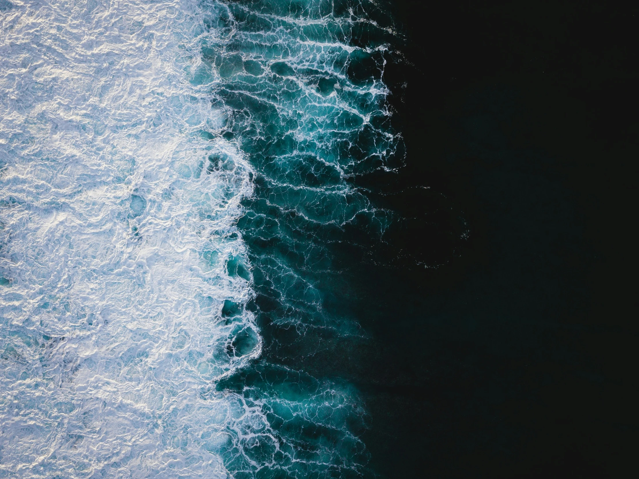 the top view of a dark ocean showing blue water