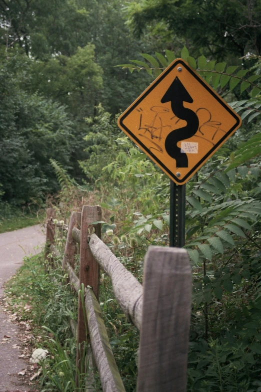 a yellow traffic sign hanging from the side of a wooden fence