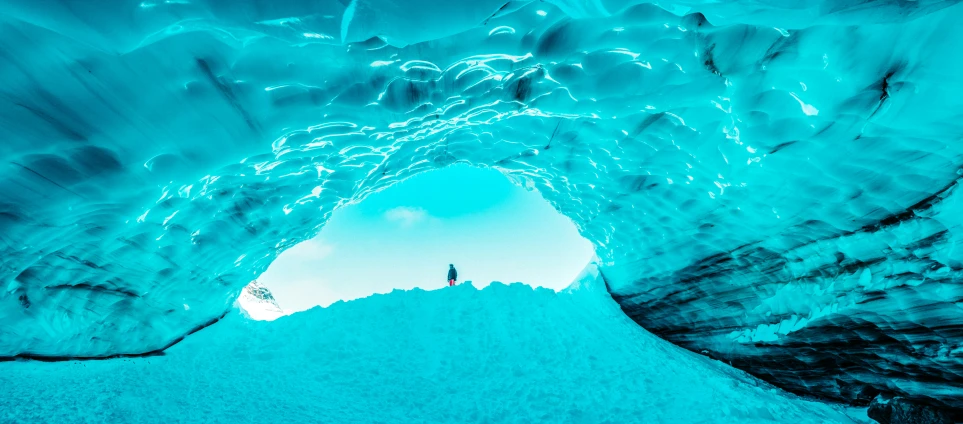 a person stands in a large ice cave