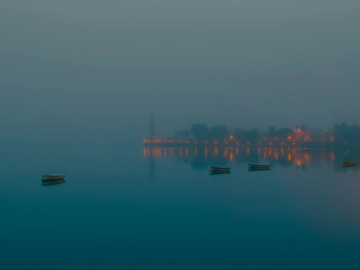 several small boats in the water with a town behind them