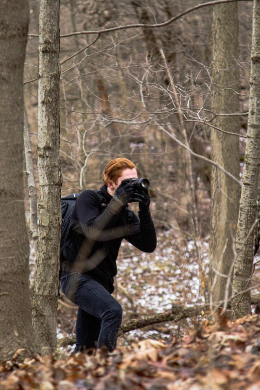 a man in black jacket holding a camera up to his face