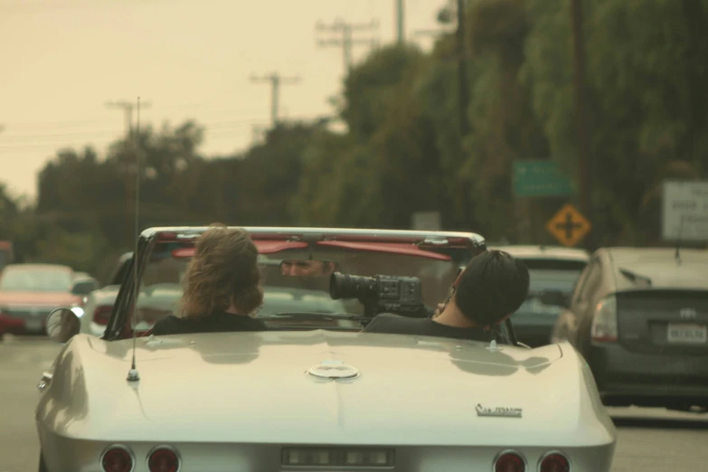 a man and woman in a convertible looking at soing