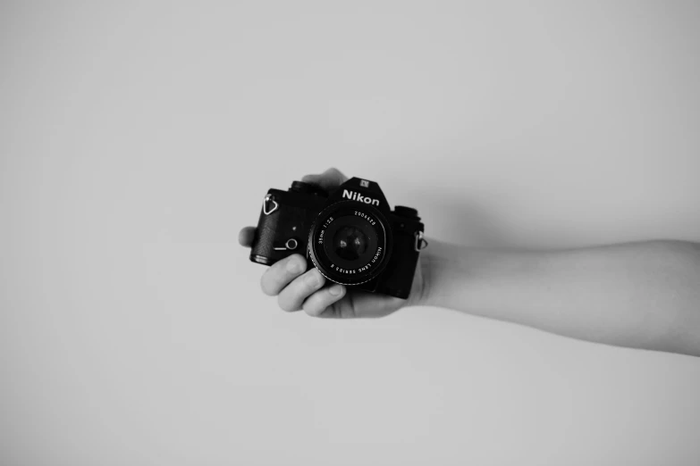 someone's hand holding an analog camera on a white background