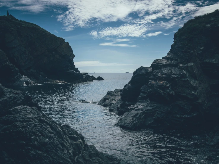 a body of water with a rocky cliff beside it