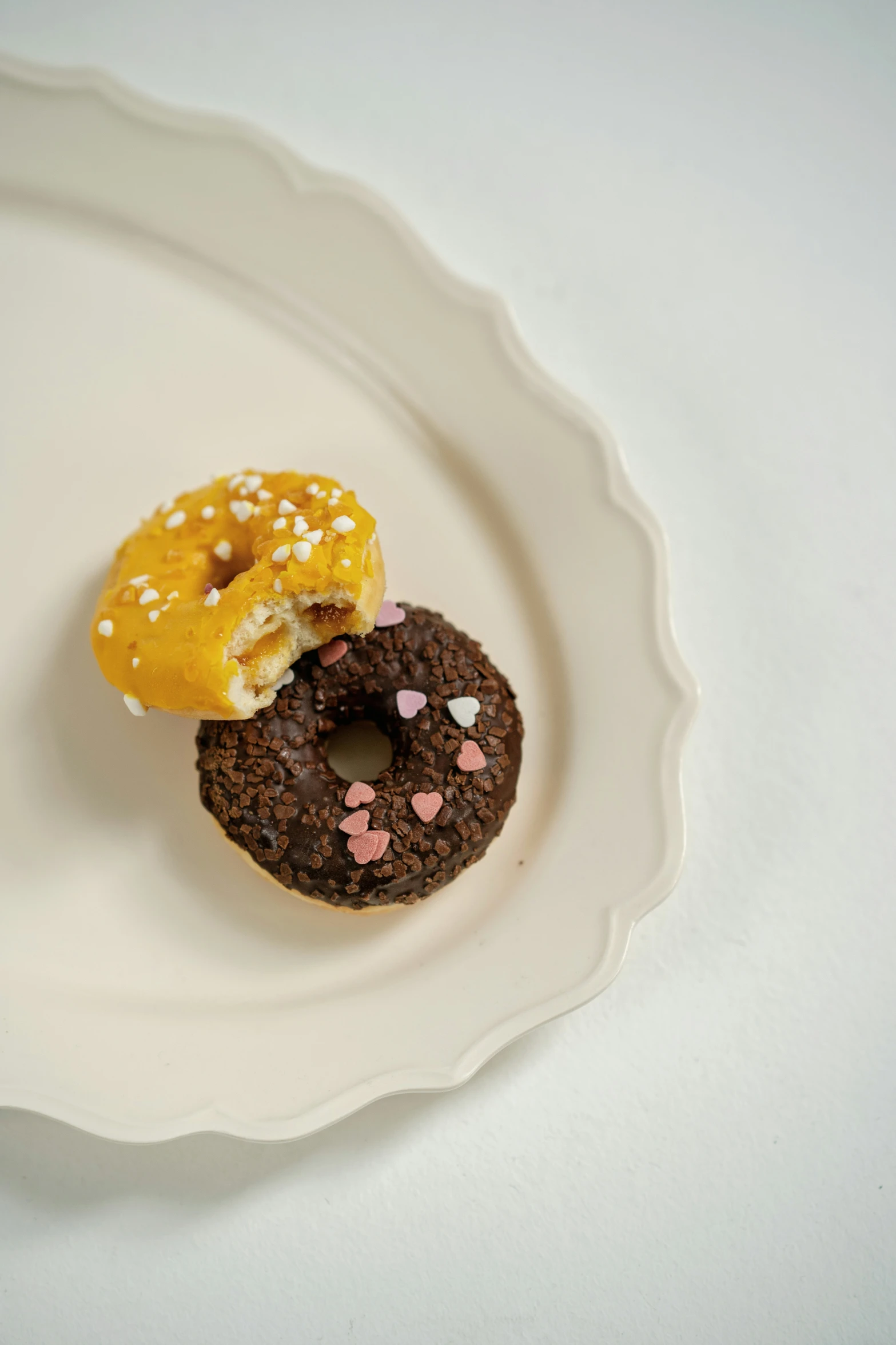 two chocolate doughnuts with sprinkles on a plate