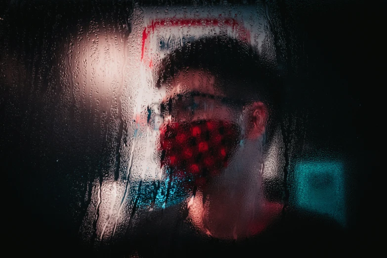 a young man in plaid fabric covered face standing by window
