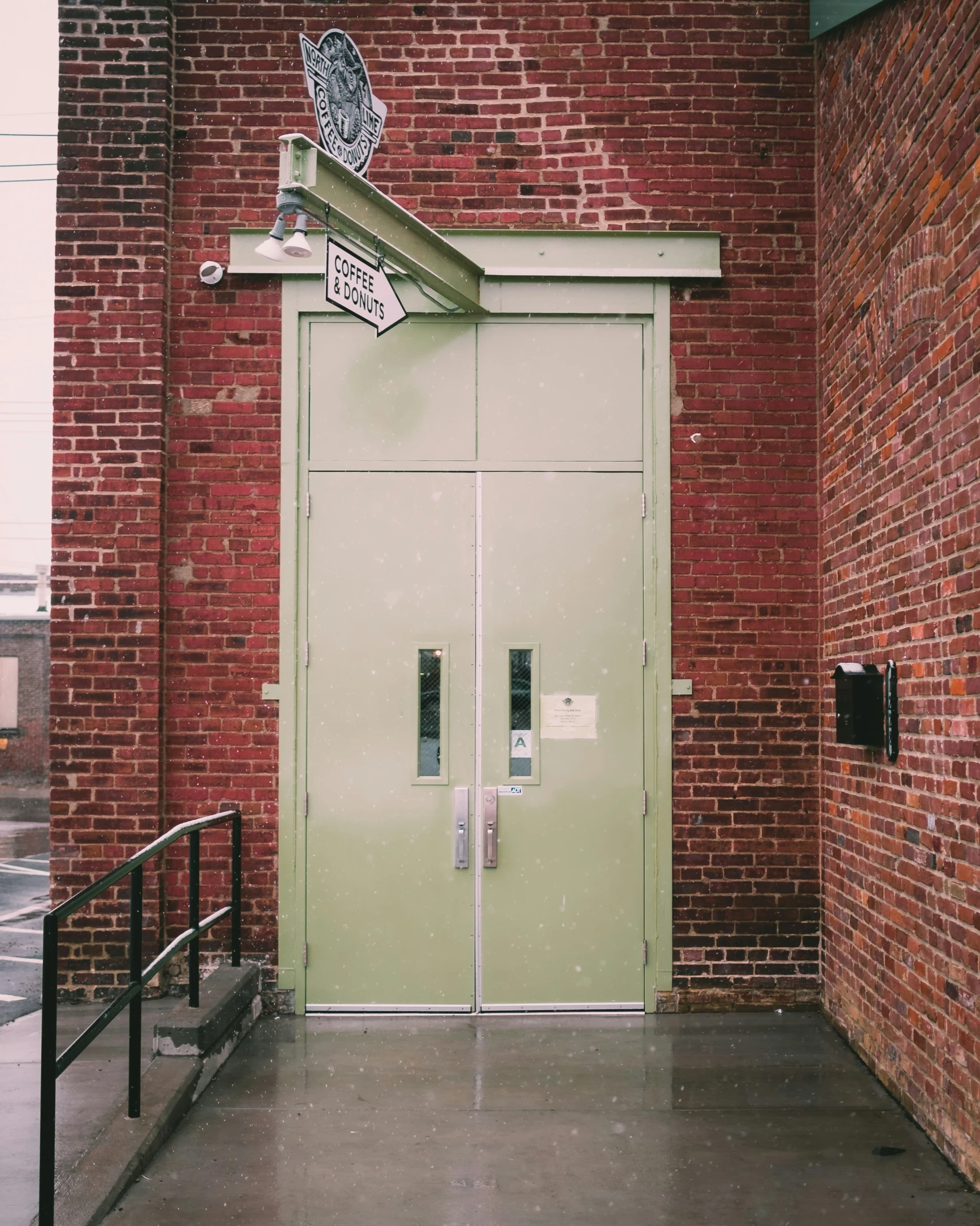 a brick building has a green door and a sign on the front