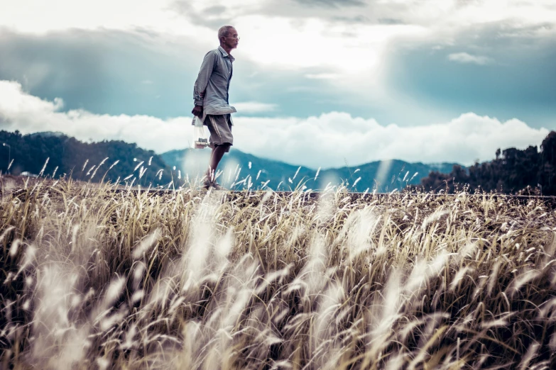 the man is standing in the tall grass looking away from the camera