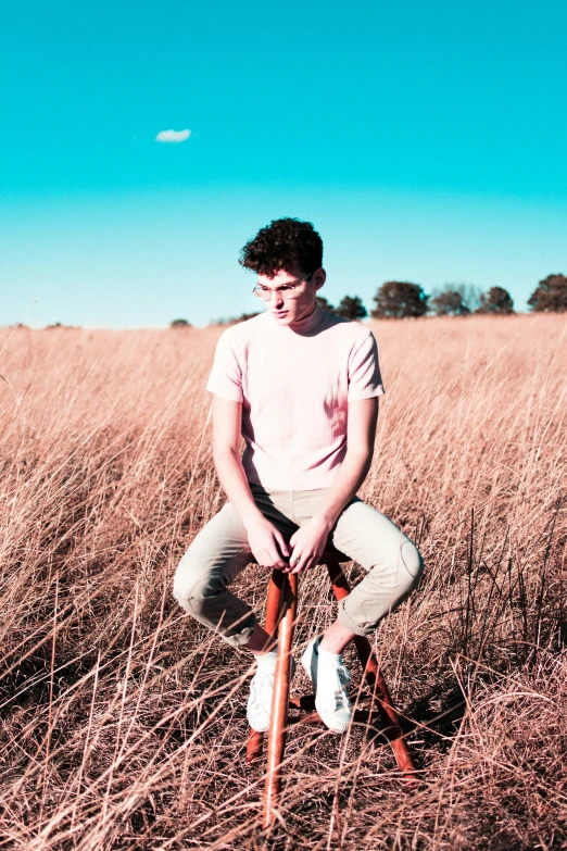 a person sitting in the grass with their leg in a chair