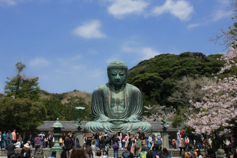 a group of people standing around a big buddha statue