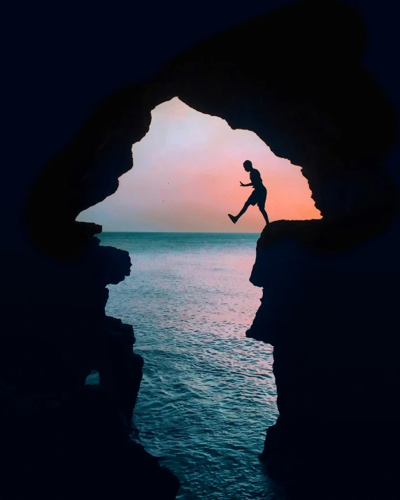 there is a silhouette of a person climbing out of a cave