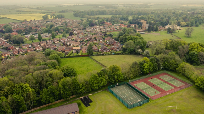 an aerial po of a tennis court in a large field