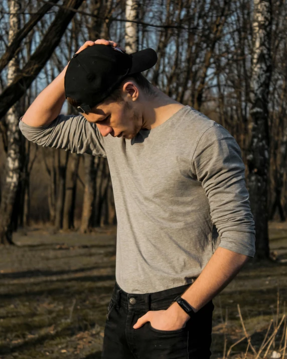 a young man standing in the woods wearing a hat