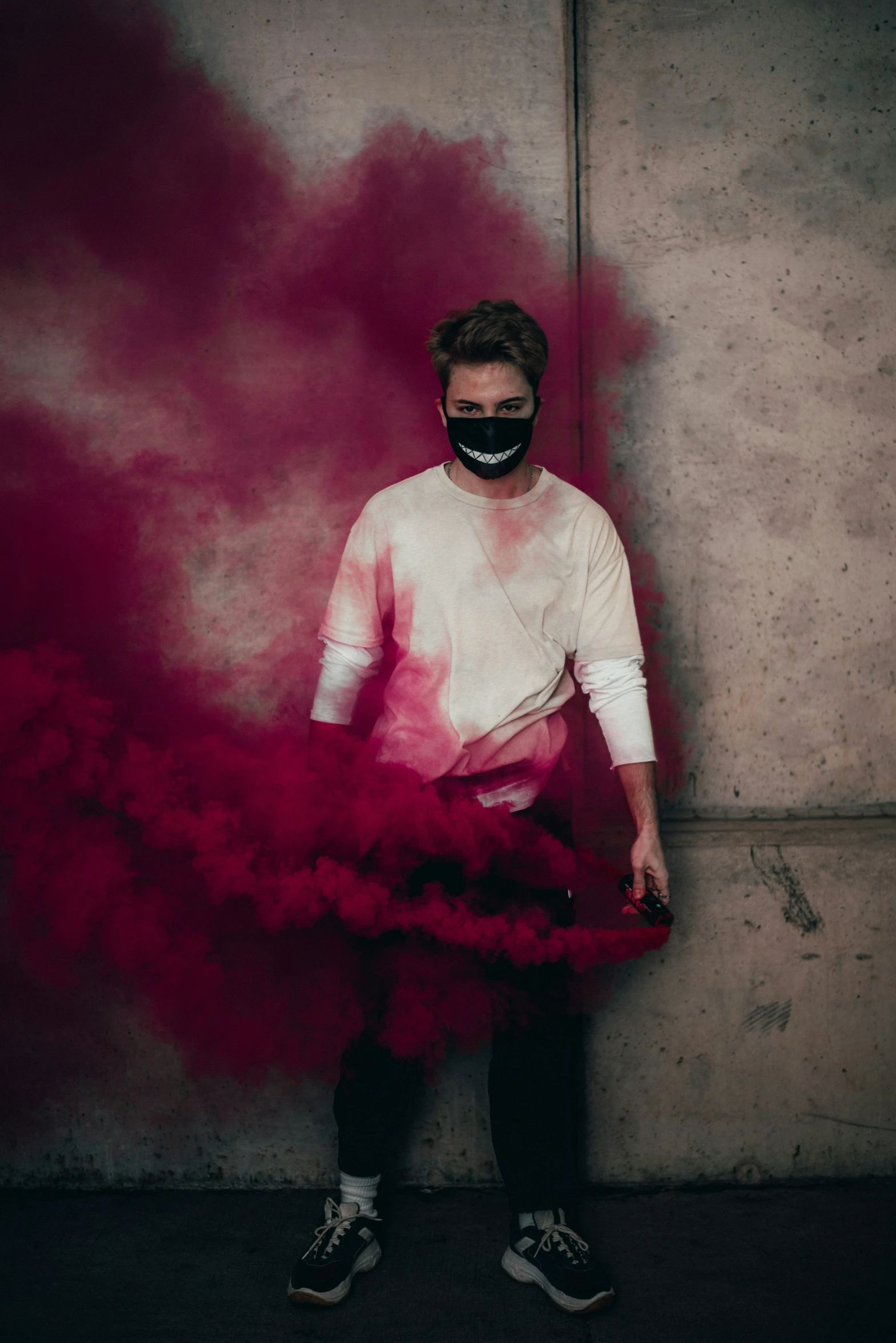 the man is wearing a mask and holding a smoke bomb