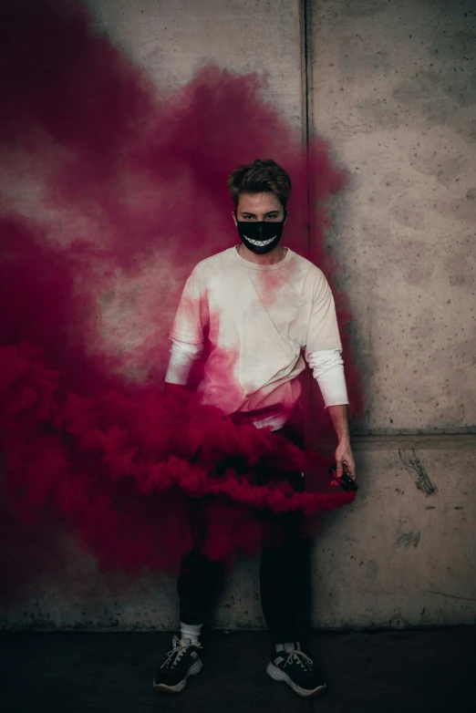 the man is wearing a mask and holding a smoke bomb