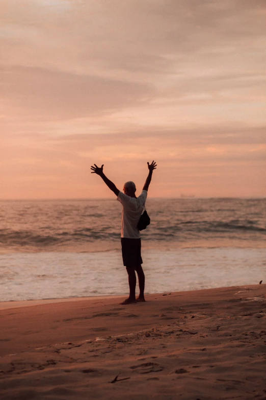 a man standing on the beach with his arms in the air