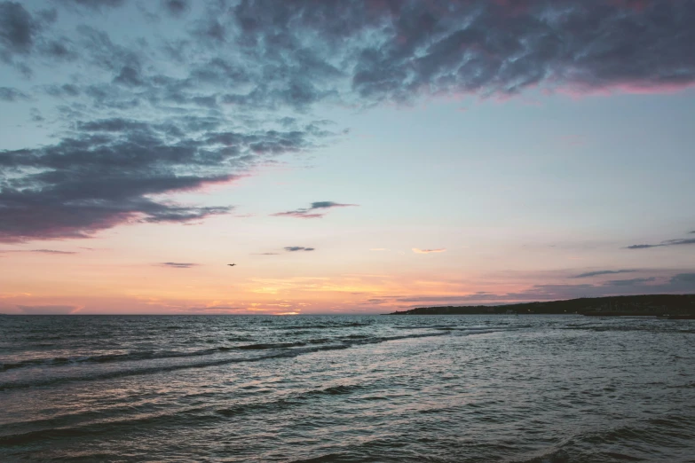 the sunset is lit up over a calm ocean