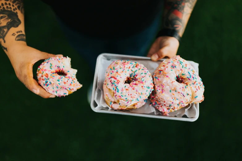 a person holding three doughnuts in a tray