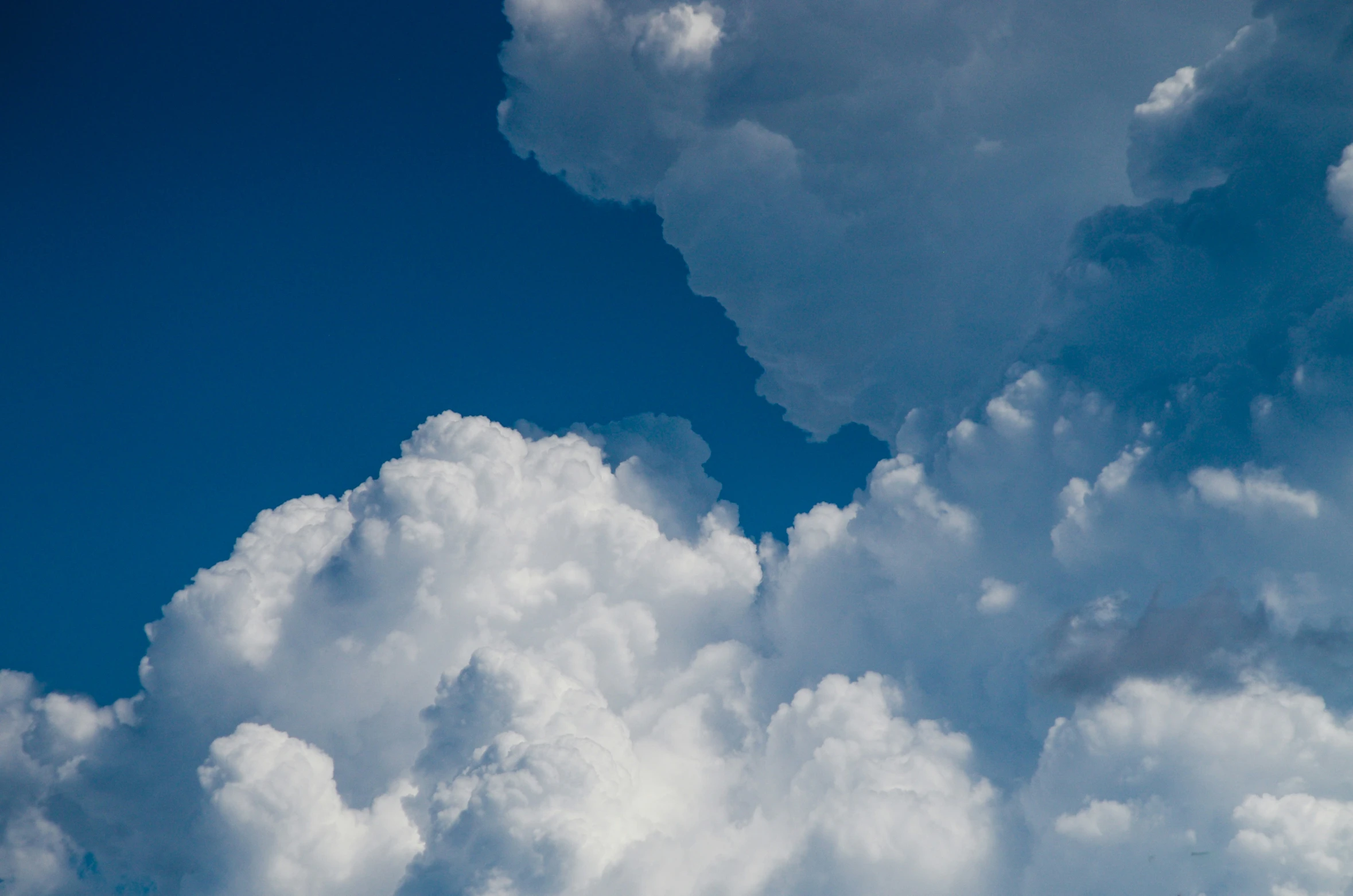 a bird flying among the clouds in a clear blue sky