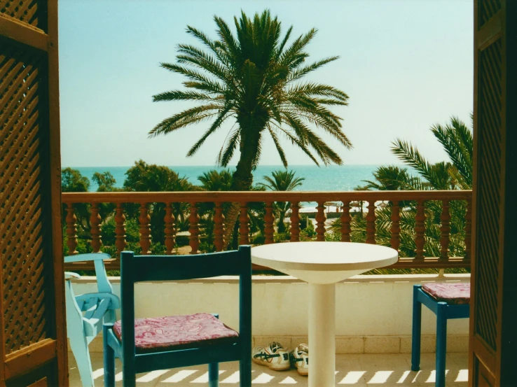 two blue chairs are on a patio next to a table with a pink cover