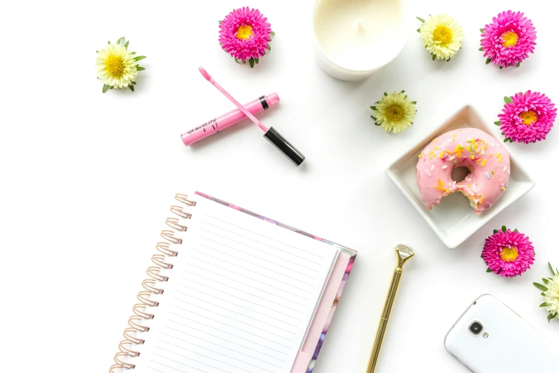 a phone and pen next to a donut