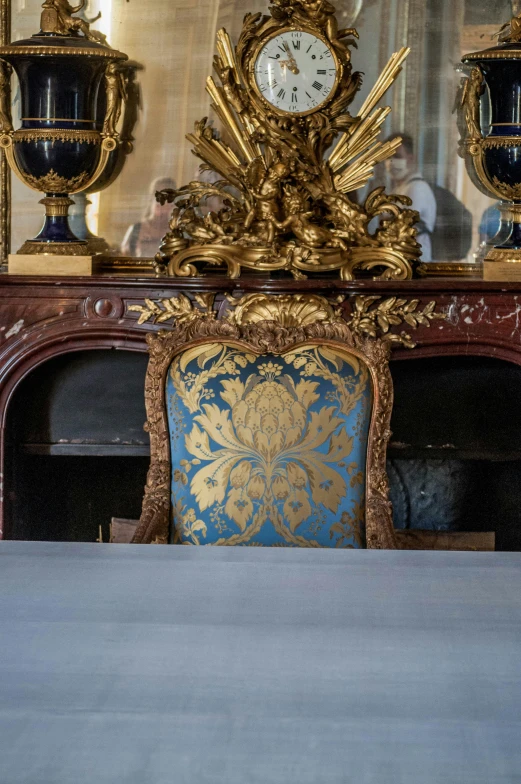 a table and chair in front of a gold mirror