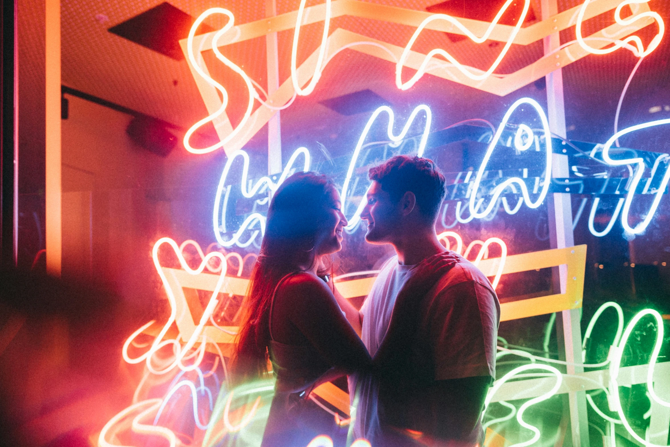 couple standing in front of colorful neon art