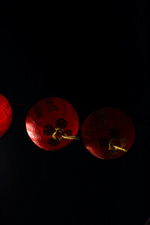 three red paper lanterns are hanging on a line