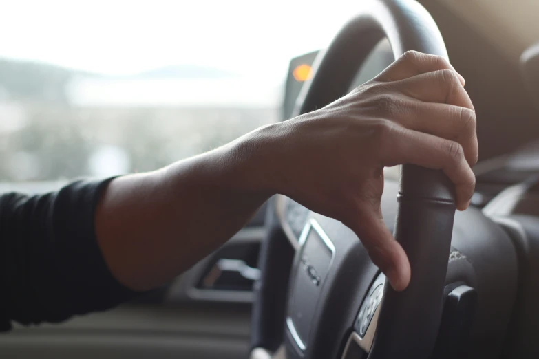 a hand holding a steering wheel on the dashboard